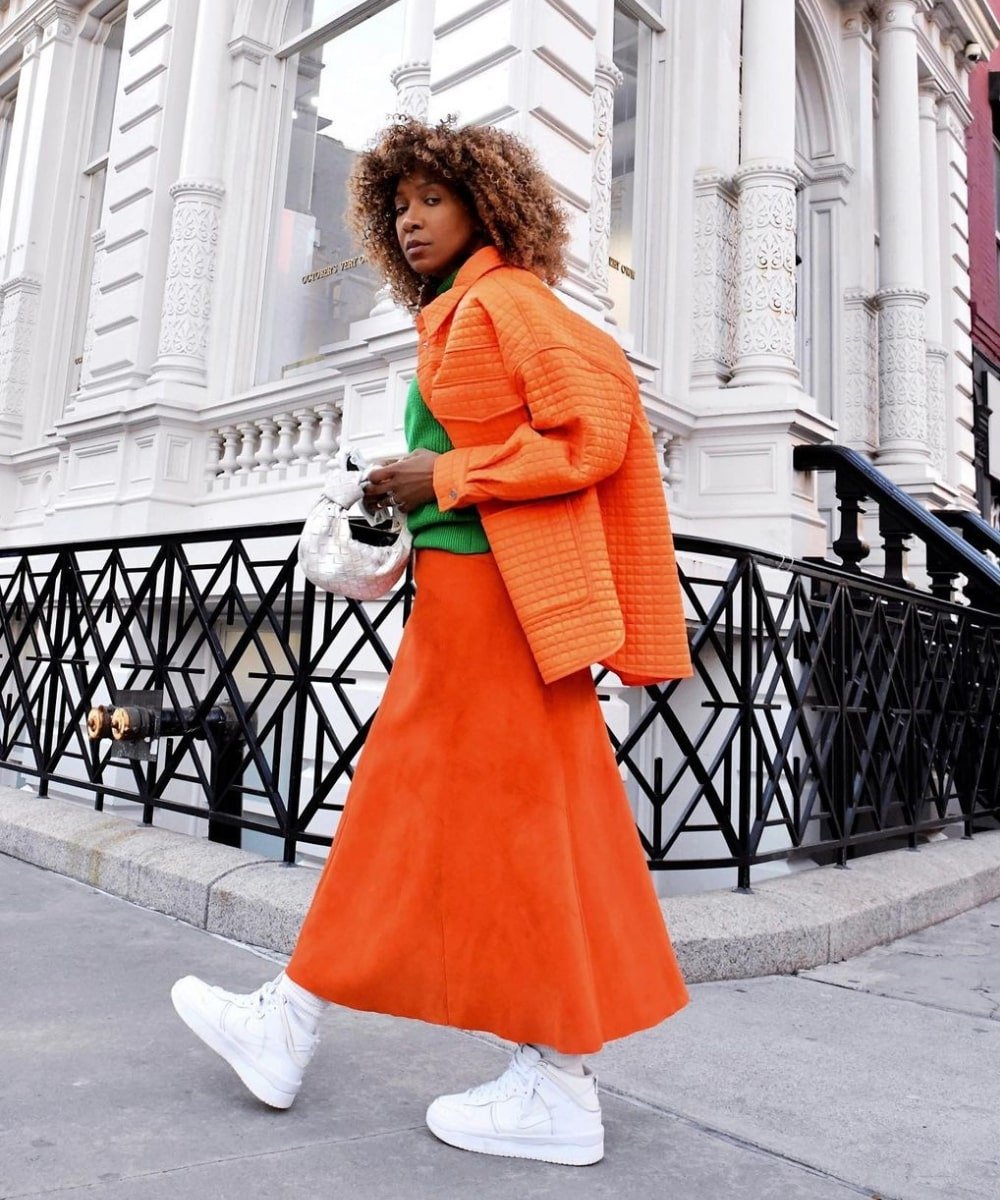 Karen Blanchard - saia longa laranja, tricot verde, tênis e jaqueta laranja - looks com saia - Inverno  - andando na rua - https://stealthelook.com.br