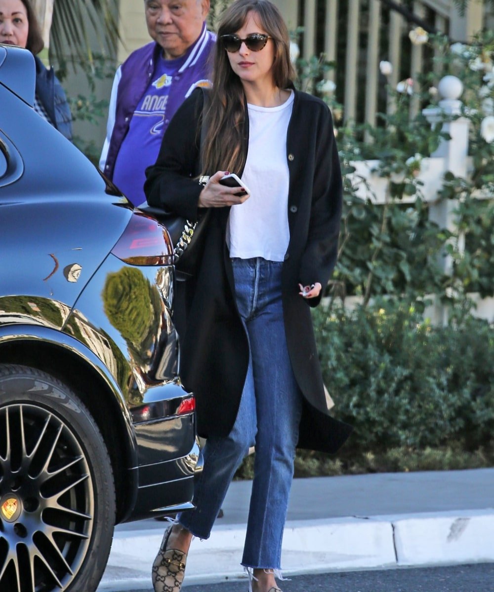 Dakota Johnson - calça jeans skinny, loafer, camiseta branca e casaco preto - Dakota Johnson - Inverno  - andando na rua usando óculos de sol - https://stealthelook.com.br