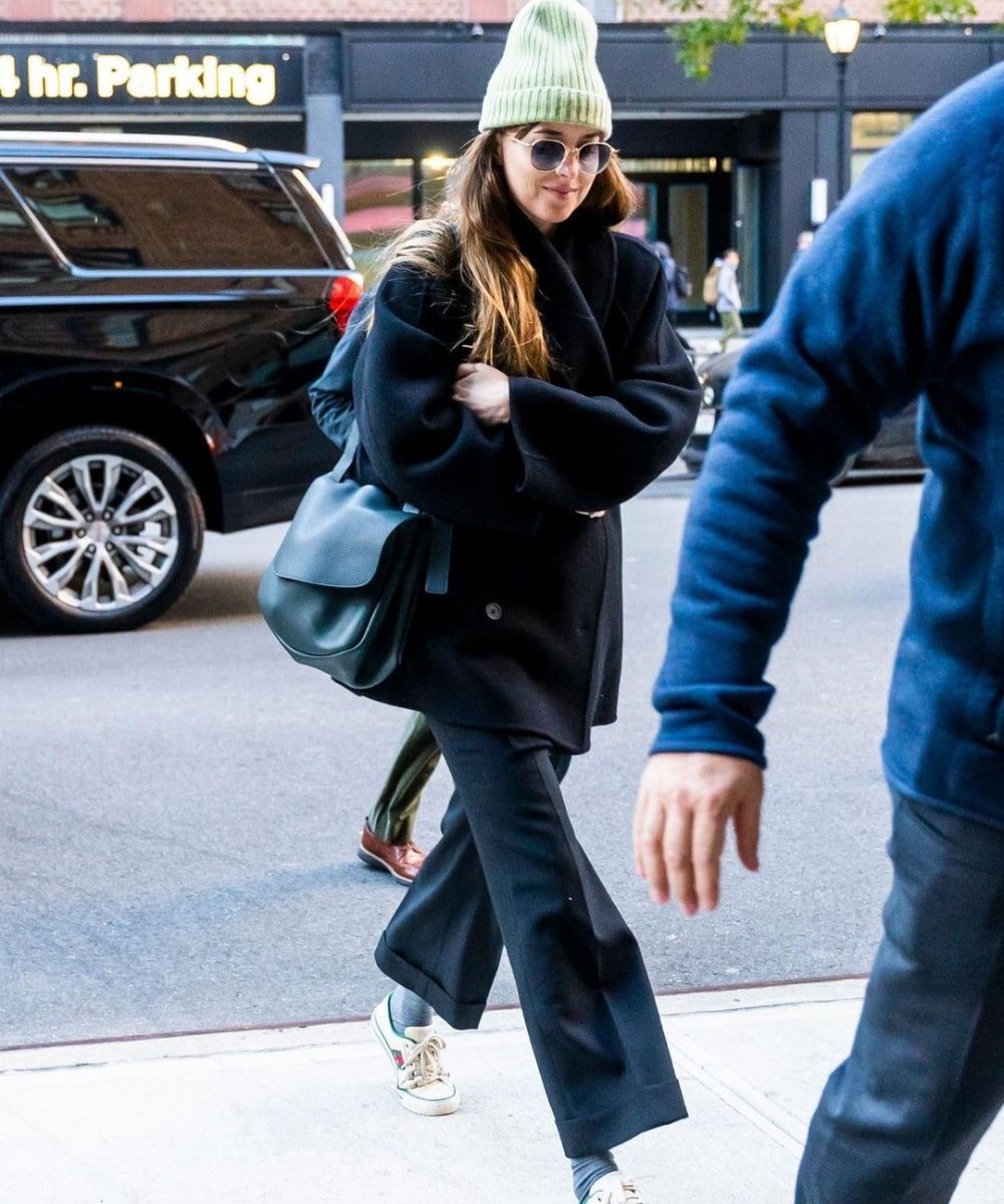 Dakota Johnson - calça preta, moletom oversized preto e gorro verde - Dakota Johnson - Inverno  - andando na rua - https://stealthelook.com.br
