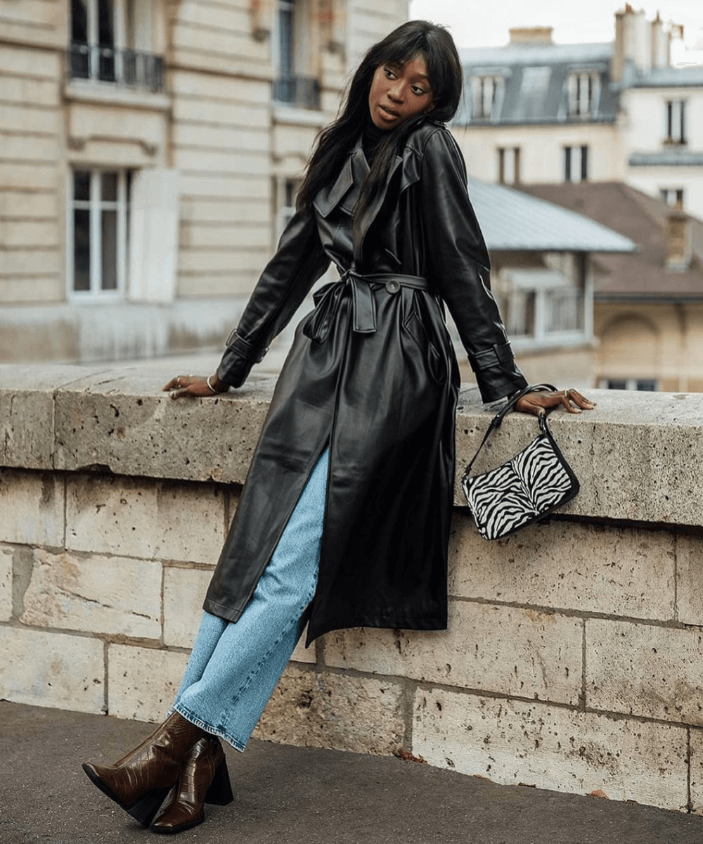 Emmanuelle Koffi - trench coat com calça jeans e bota - looks com trench coat - Inverno 2022 - apoiada na ponte - https://stealthelook.com.br