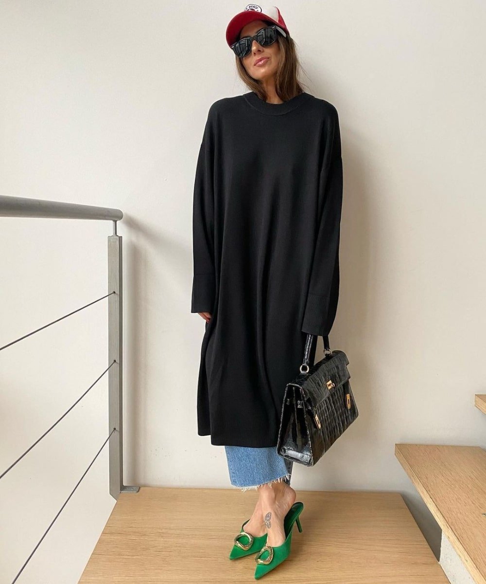 Laura Eguizabal - calça jeans azul, vestido preto de manga longa e scarpin verde - looks oversized - Outono - em pé em uma sala usando um boné - https://stealthelook.com.br