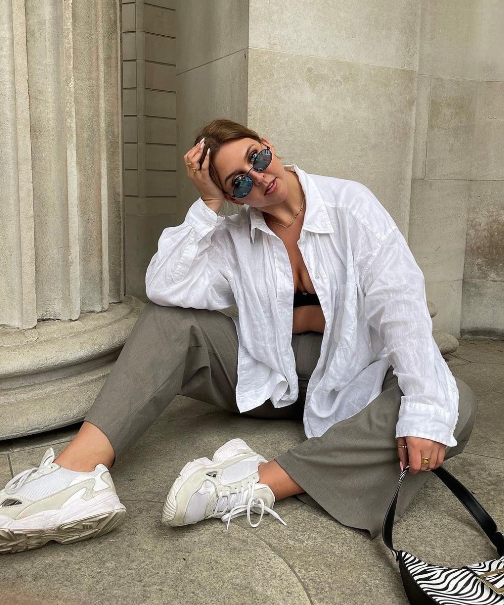 Madison | @Madisoneley - calça ampla marrom e camisa oversized branca - looks oversized - Verão - sentada na rua usando óculos de sol - https://stealthelook.com.br
