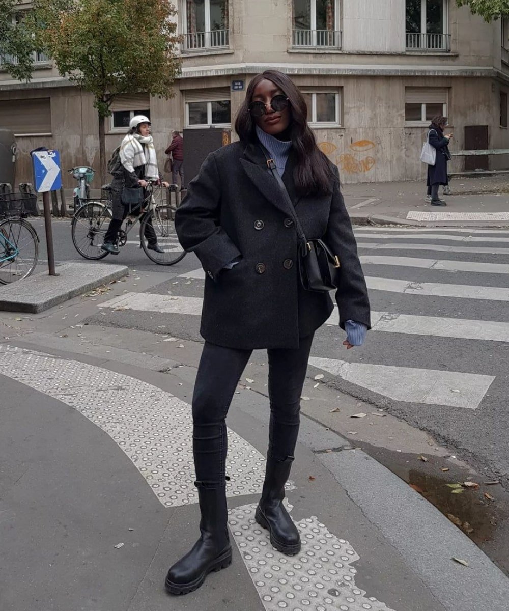 Aïda Badji Sané - calça skinny preta, casaco cinza e bota tratorada preta - calça jeans skinny - Inverno  - em pé na rua usando óculos de sol - https://stealthelook.com.br