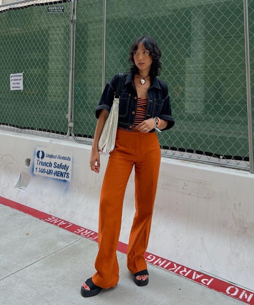 Stephanie Arant - calça laranja, blusa animal print e jaqueta jeans - looks novos - Outono - em pé na rua - https://stealthelook.com.br