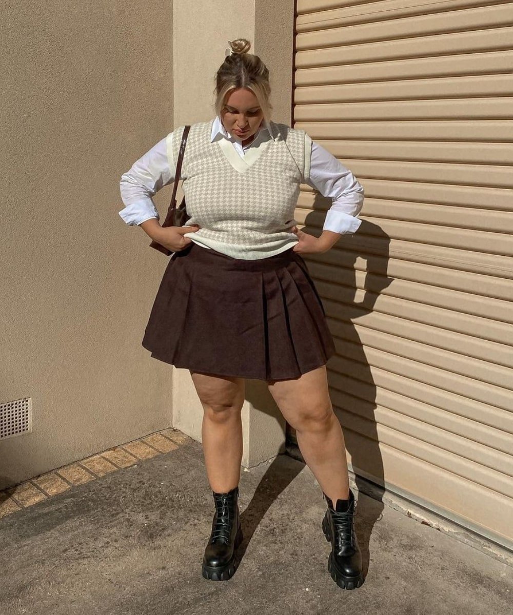 Mikaela Reidy - saia xadrez, camisa branca, colete de tricô e botas - Old Money - Outono - em pé na rua - https://stealthelook.com.br