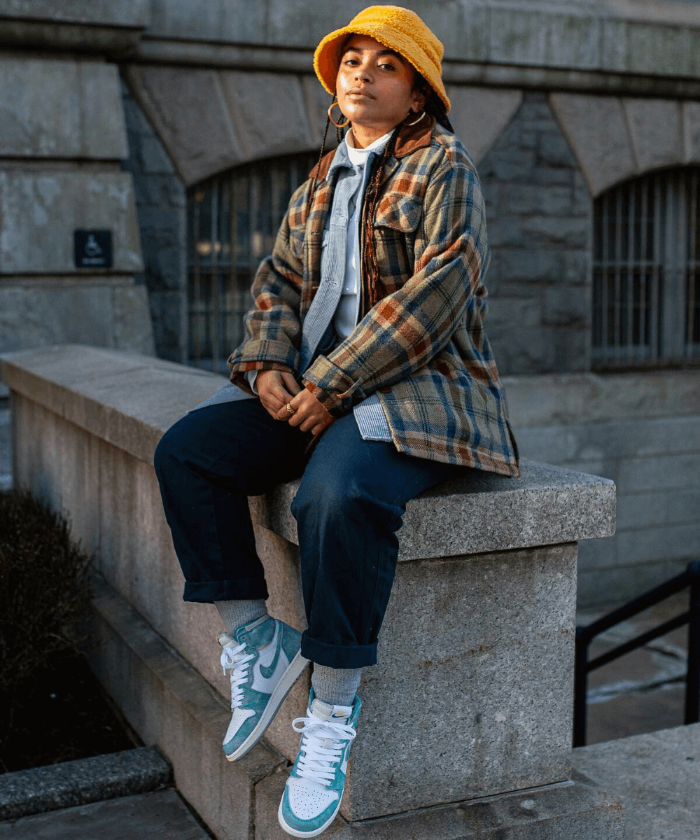 Veronica Bonilla - jaqueta xadrez com calça jeans e meia aparente - calças jeans - Inverno 2022 - sentada no muro - https://stealthelook.com.br
