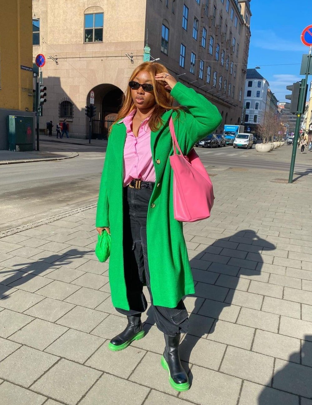 Nnenna Echem - calça cargo preta, bota chelsea, camisa rosa e sobretudo verde - calça cargo - Inverno  - em pé na rua - https://stealthelook.com.br