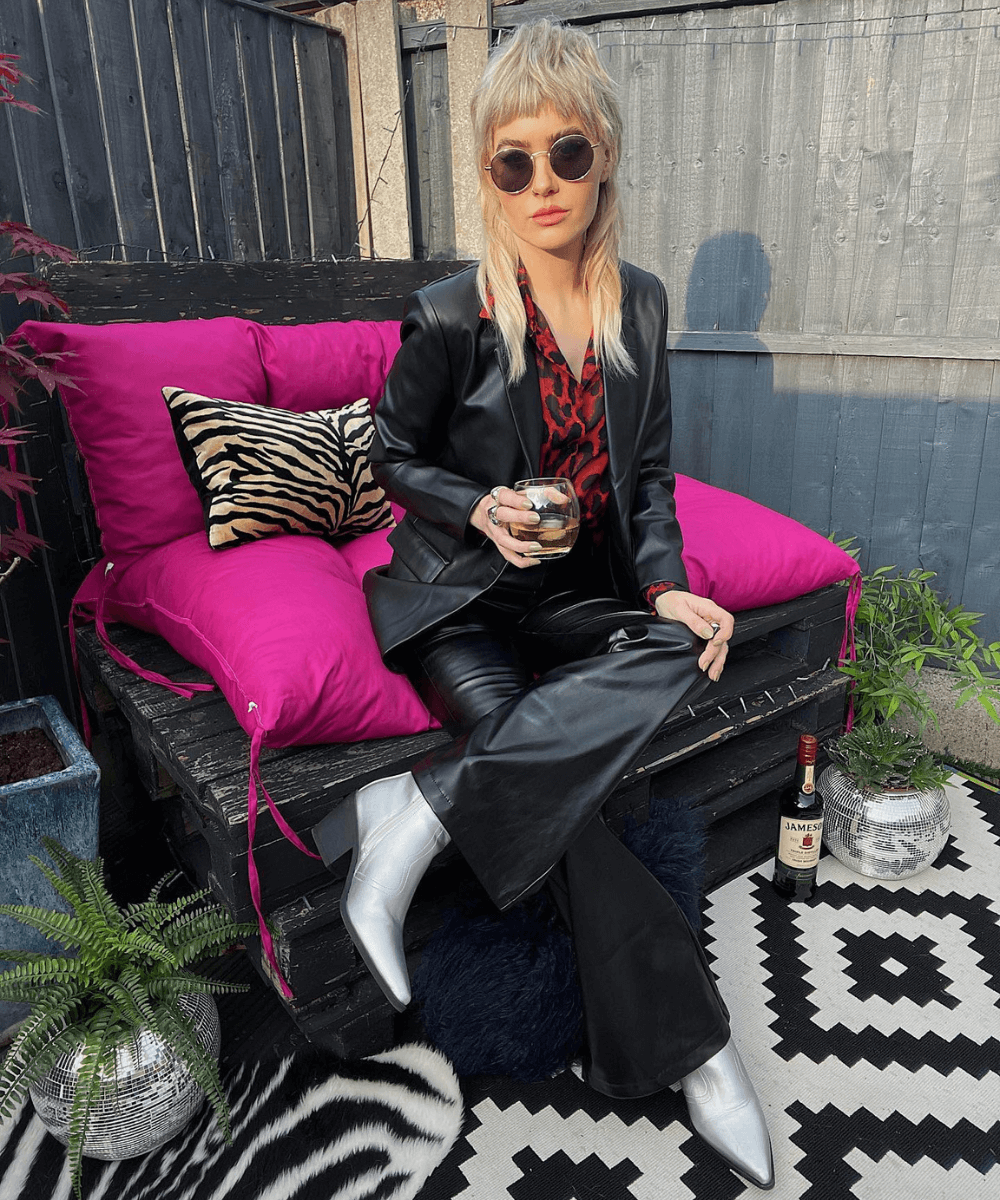 Amy Sequins - set de couro com camisa estampada - estilo rocker - Inverno 2022 - sentada na cadeira - https://stealthelook.com.br