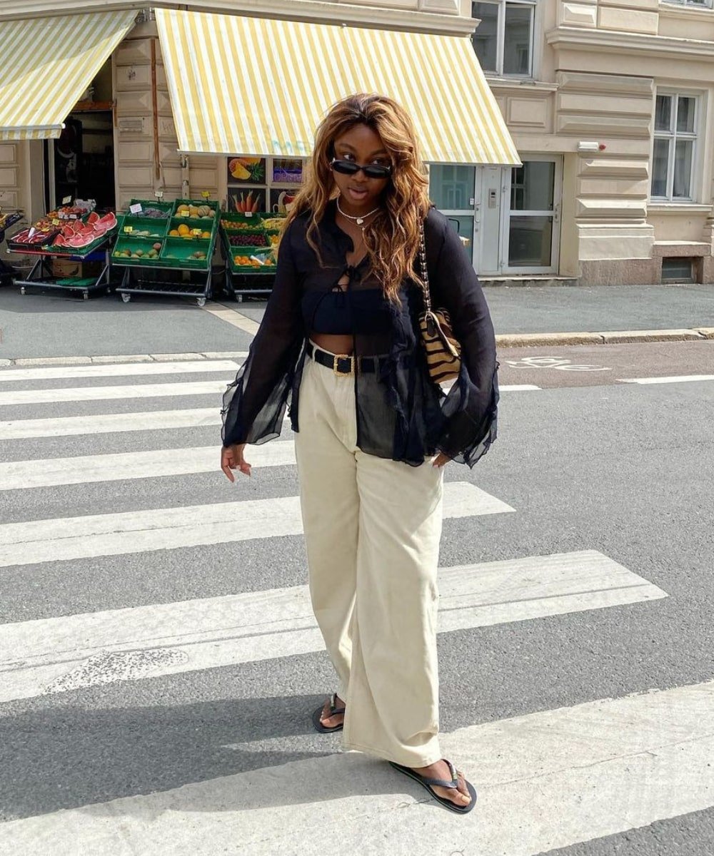 Nnenna Echem - calça bege, cropped preto e blusa transparente, chinelos e óculos - looks novos - Verão - em pé na rua - https://stealthelook.com.br