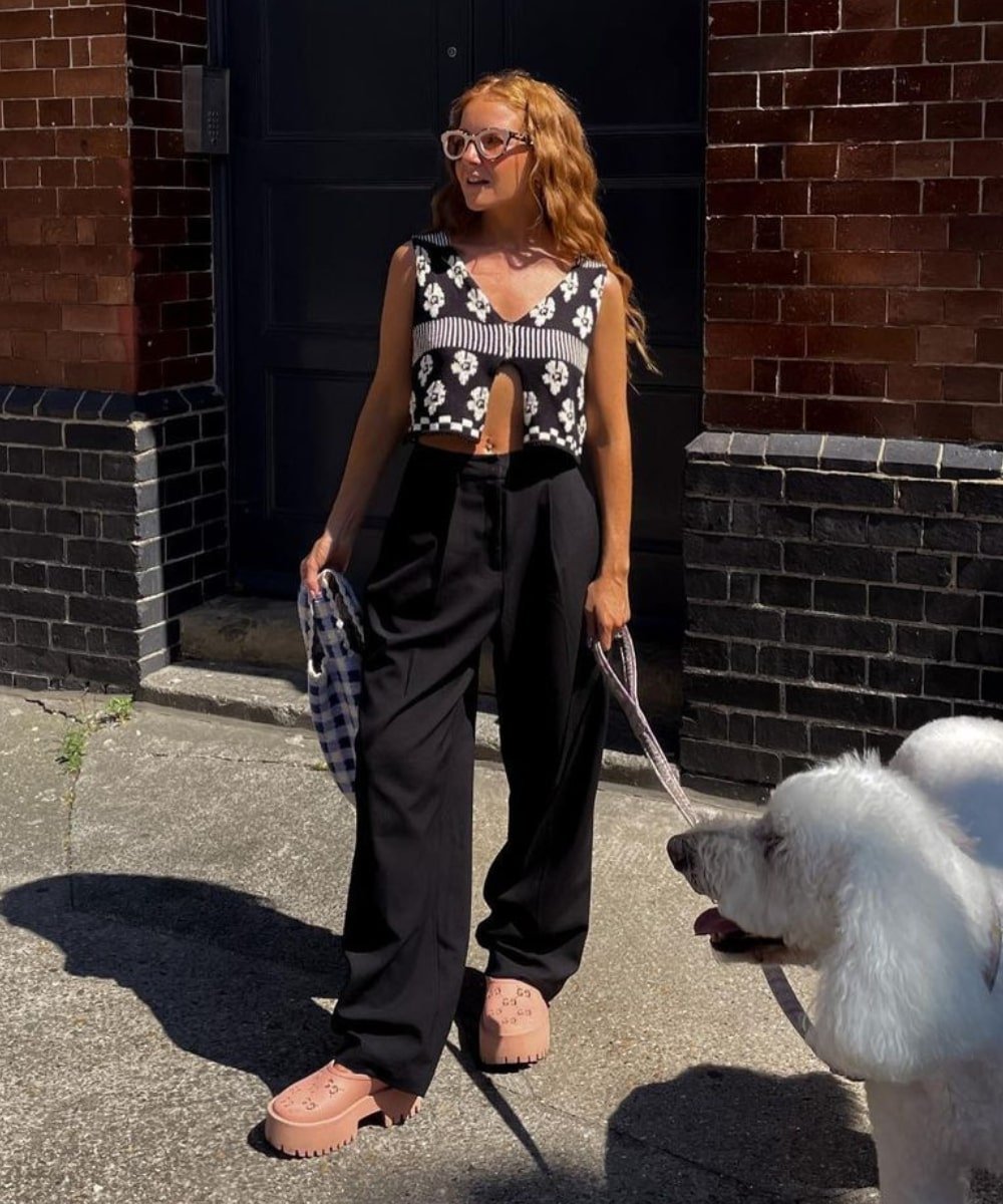Rebecca Olivia | @rebeccaferrazwyatt - calça de alfaiataria preta, cropped de tricot e clog rosa - looks com preto - Verão - em pé na rua com um cachorro do lado - https://stealthelook.com.br