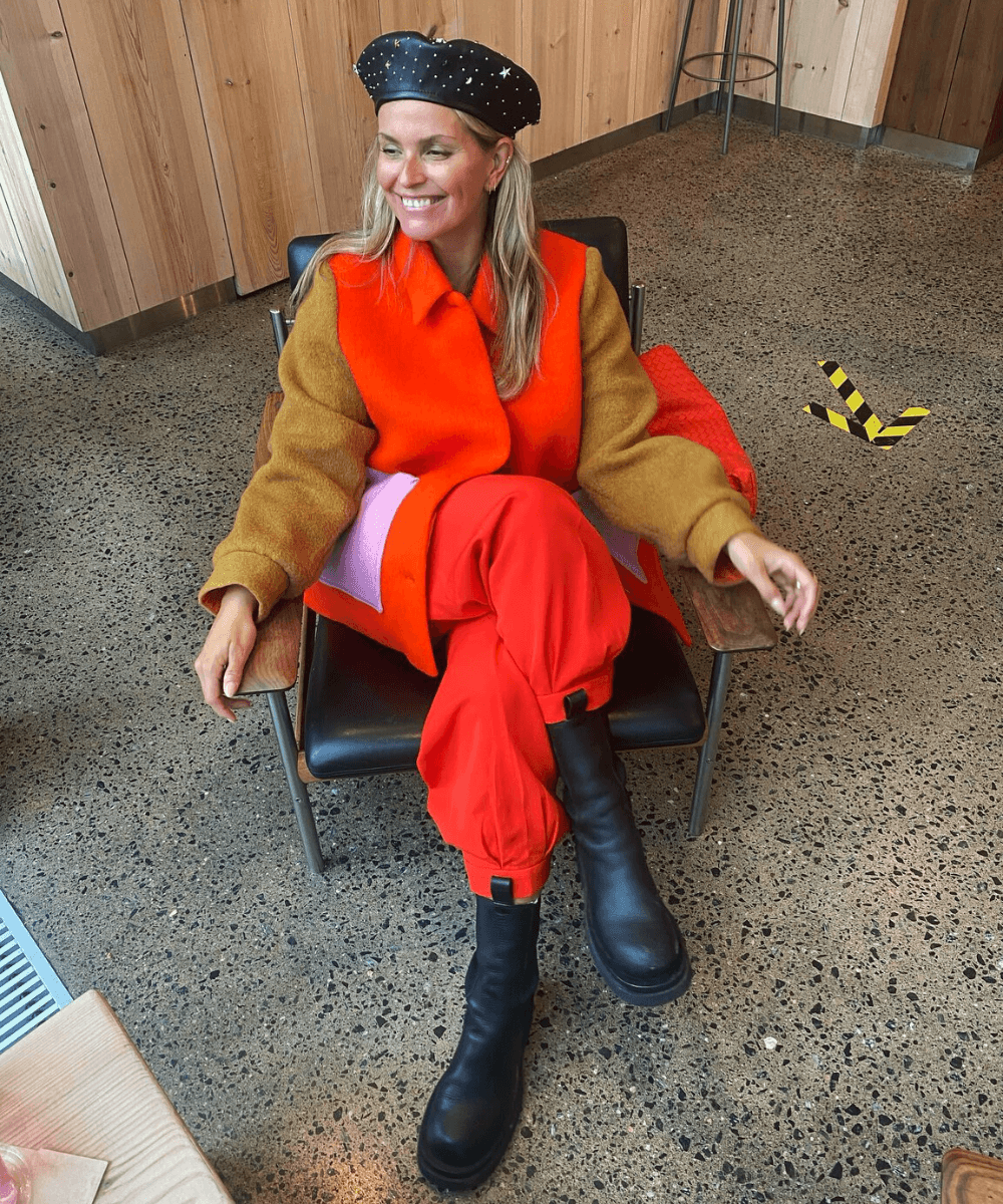 Janka Polliani - casaco laranja e calça vermelha - cores tendência - Inverno 2022 - sentada no banco - https://stealthelook.com.br