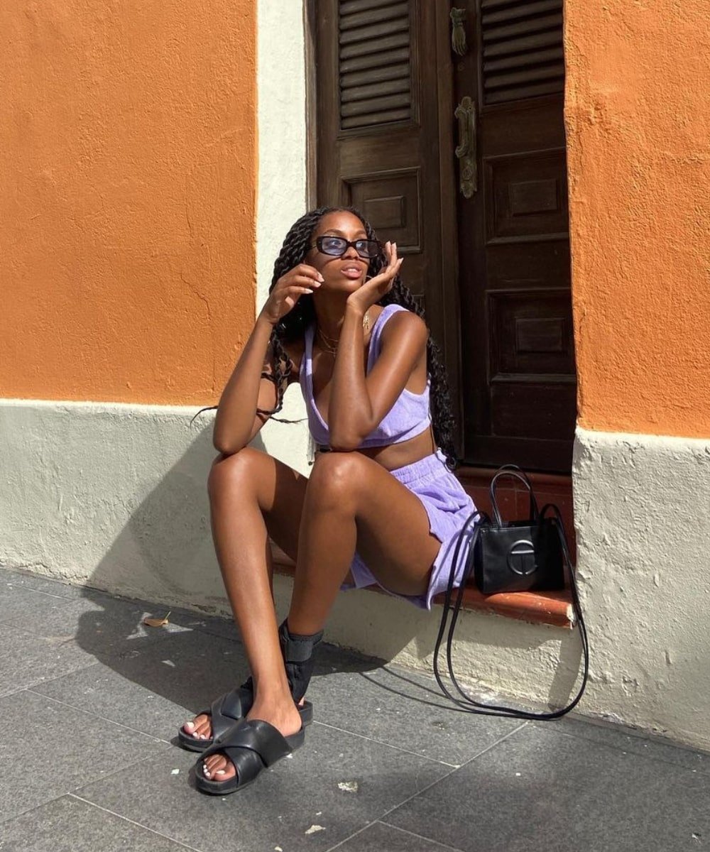 Claire Most - Conjunto lilas de short e top, rasteira preta e bolsa preta - como usar bolsa - verão  - sentada na rua usando óculos de sol - https://stealthelook.com.br