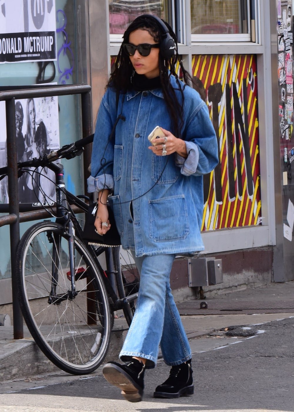 Zoë Kravitz - calça jeans, jaqueta jeans e coturno preto - looks básicos - Outono - andando na rua usando óculos de sol - https://stealthelook.com.br