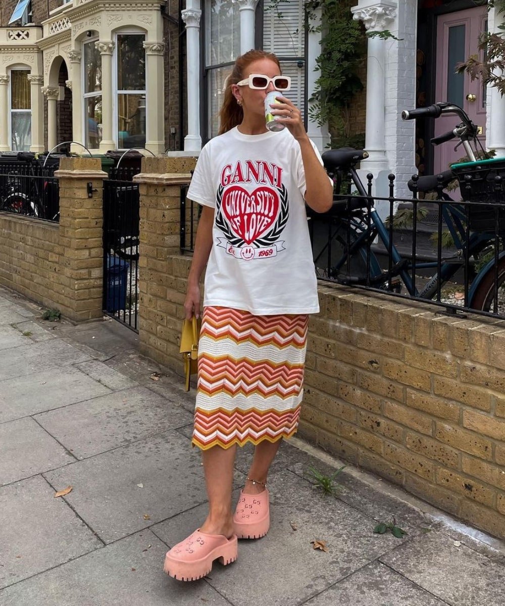 Rebecca Olivia | @rebeccaferrazwyatt - saia midi, tshirt estampada e clog rosa - saia midi - Verão - em pé na rua usando óculos de sol - https://stealthelook.com.br