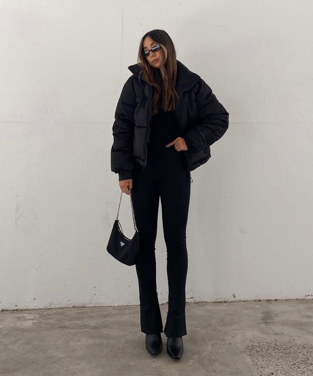 Kristy Wu - calça preta, jaqueta puffer preta, óculos de sol e bolsa - calça tendência - Inverno  - em pé na rua usando óculos de sol - https://stealthelook.com.br