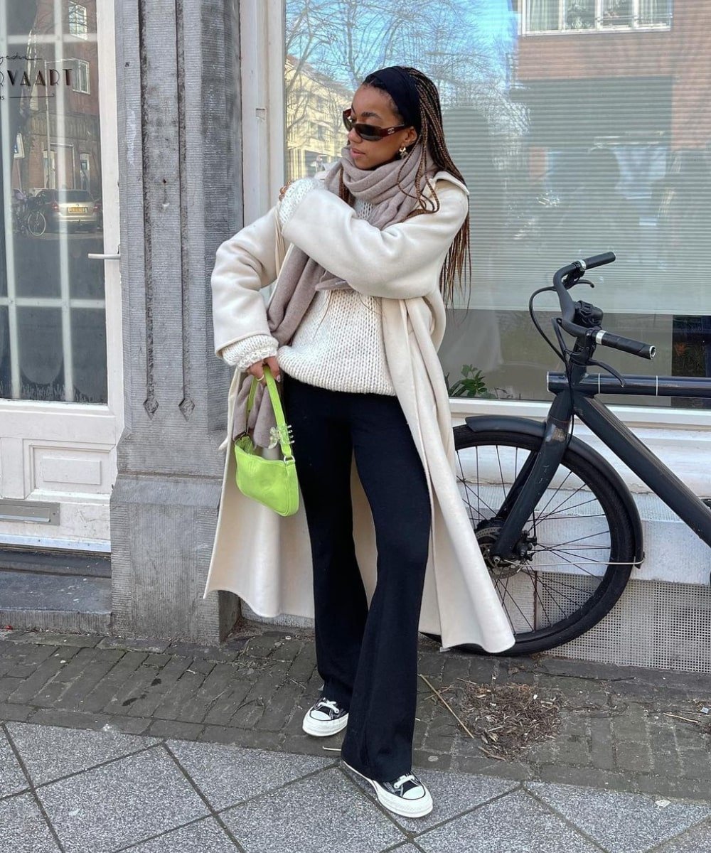 Amaka Hamelijnck - calça flare preta, casaco off white, tênis converse e bolsa verde baguete - calça tendência - Inverno  - em pé na rua - https://stealthelook.com.br