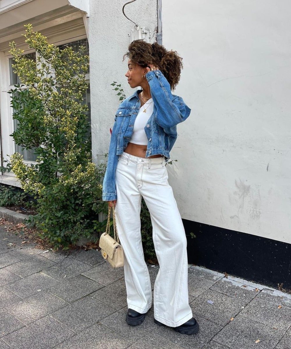 Amaka Hamelijnck - calça flare branca, top branco e jaqueta jeans - looks novos - Primavera - em pé na rua - https://stealthelook.com.br