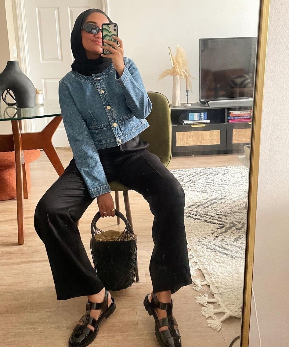 Yusra Siddiqui - calça preta, jequeta jeans, sandália fisherman e óculos escuros - looks novos - Outono - foto na frente do espelho - https://stealthelook.com.br