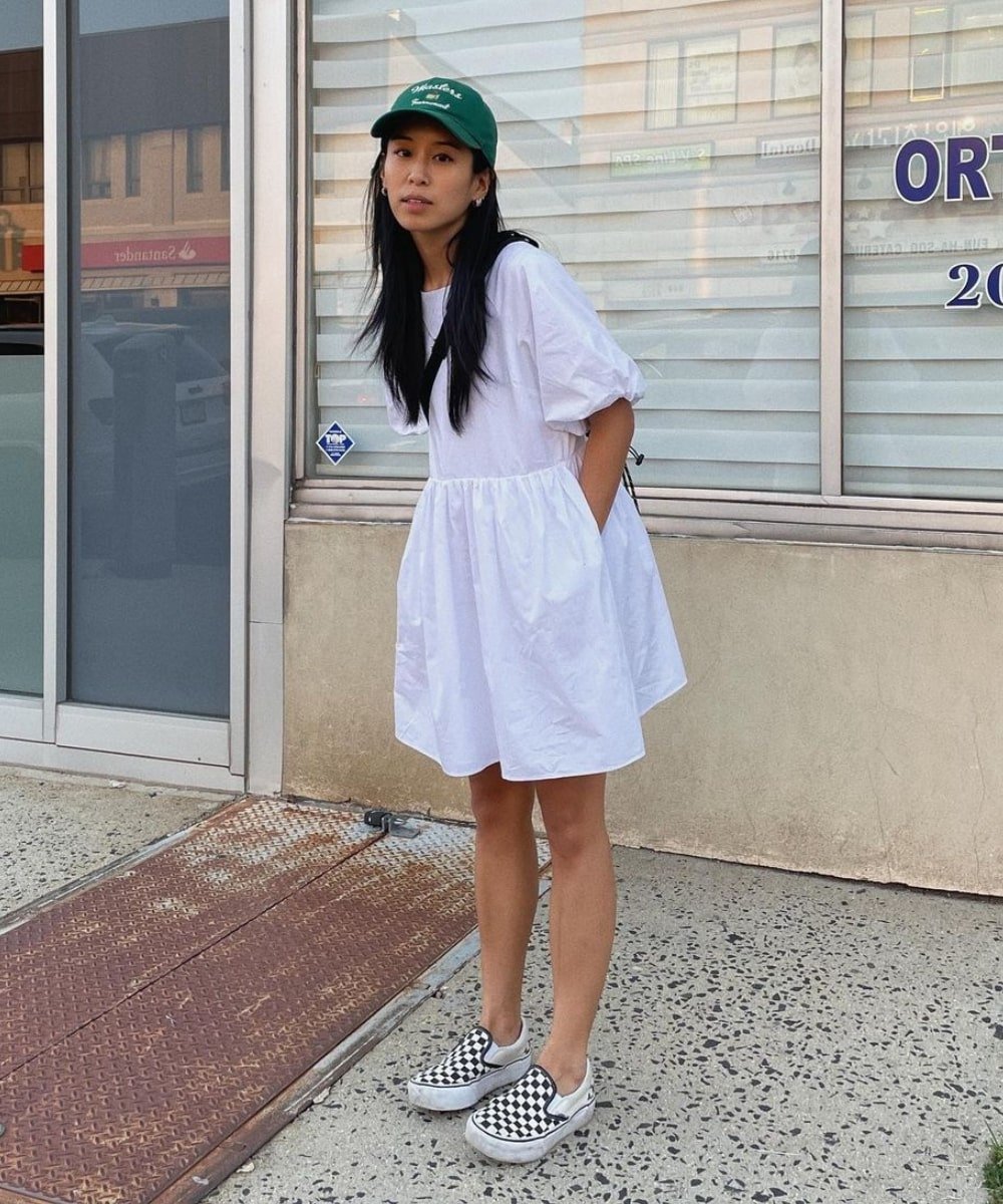 Kristen Lam - vestido curto branco, tênis xadrez e boné verde - verão 2023 - Verão - em pé na rua - https://stealthelook.com.br