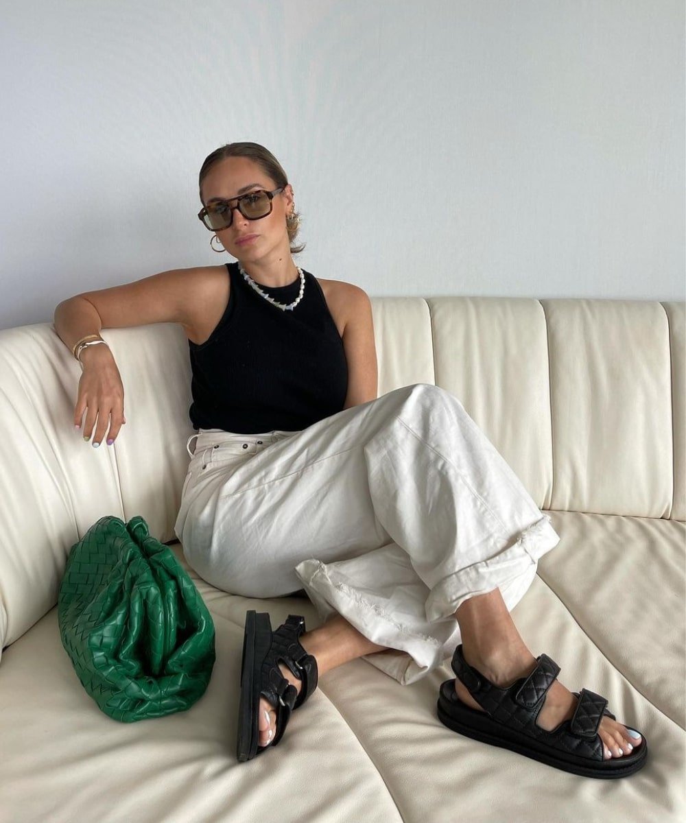 Olivia Faeh - calça off white loose, regata preta e óculos de sol - primavera 2023 - Primavera - sentada em um sofá usando oculos escuros - https://stealthelook.com.br