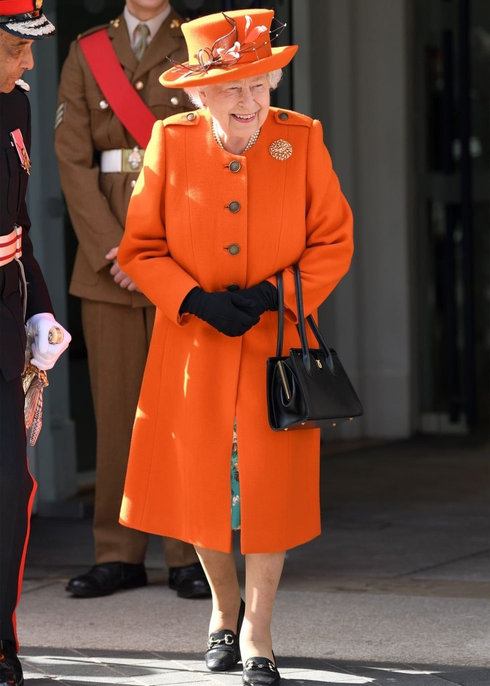 Rainha Elizabeth II - conjunto de alfaiataria laranja, chapéu e luvas pretas - Rainha Elizabeth II - Outono - andando na rua - https://stealthelook.com.br