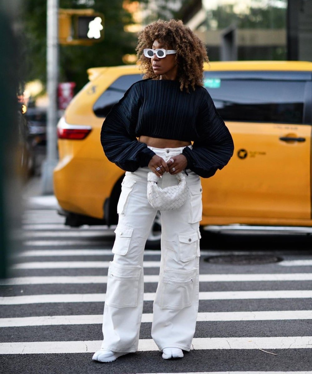 Karen Blanchard - calça cargo branca, blusa de manga longa preta e óculos - tendências de moda - Primavera - em pé na rua usando óculos de sol - https://stealthelook.com.br