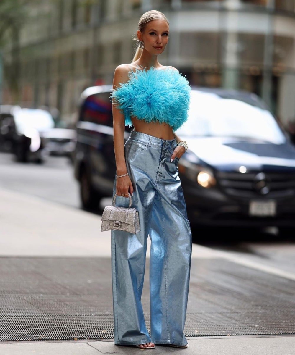 Leonie Hanne - calça metalizada azul, top de plumas e salto alto - looks metalizados - Verão - em pé na rua - https://stealthelook.com.br