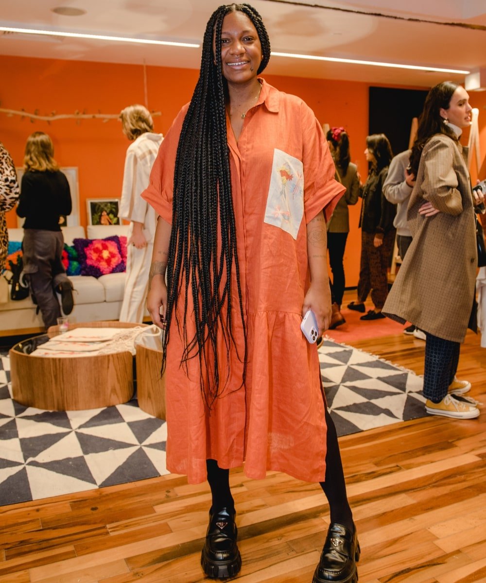 Luanda Vieira - vestido laranja estilo chemise, meia-calça e loafer tratorado preto - Festival Nordestesse - Outono - em pé dentro de uma loja - https://stealthelook.com.br