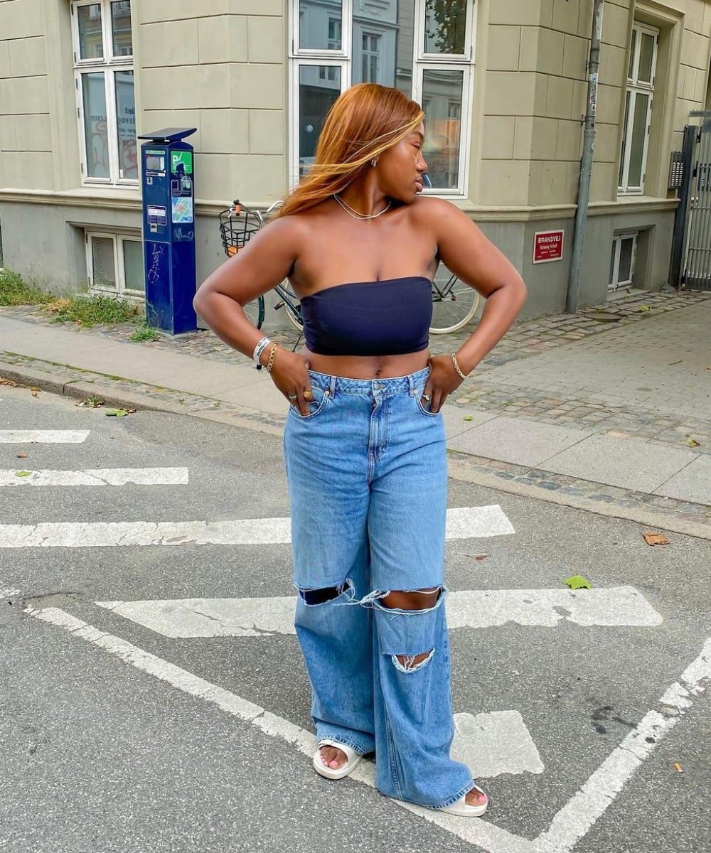 Nnenna Echem - calça jeans, top preto e chinelo - looks com jeans - Verão - em pé na rua olhando para o lado - https://stealthelook.com.br