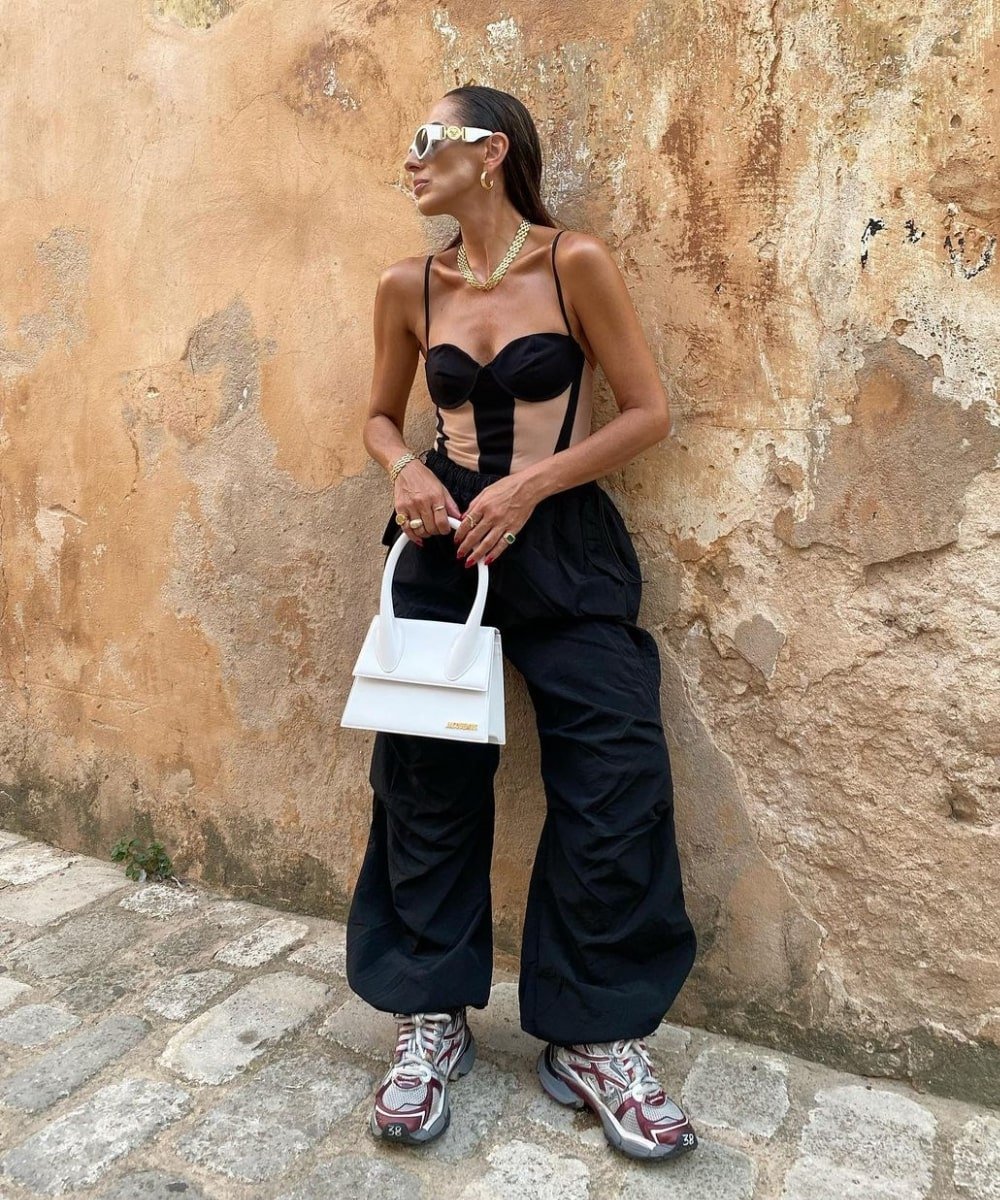 Laura Eguizabal - calça baggy preta, body, óculos e tênis - looks com tênis esportivos - Verão - em pé na rua usando óculos de sol - https://stealthelook.com.br