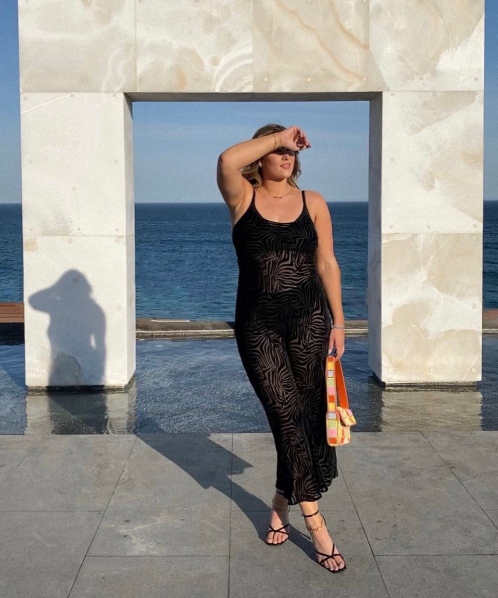 Rae Everyday - vestido preto midi rendado - looks de praia - Verão - em pé na rua com o mar de fundo - https://stealthelook.com.br
