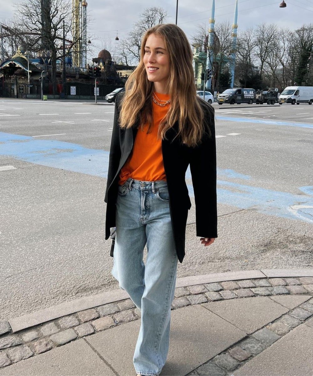 Annabel Rosendahl - calça jeans, blusa laranja, blazer preto e sandálias - looks coloridos - Outono - andando na rua - https://stealthelook.com.br