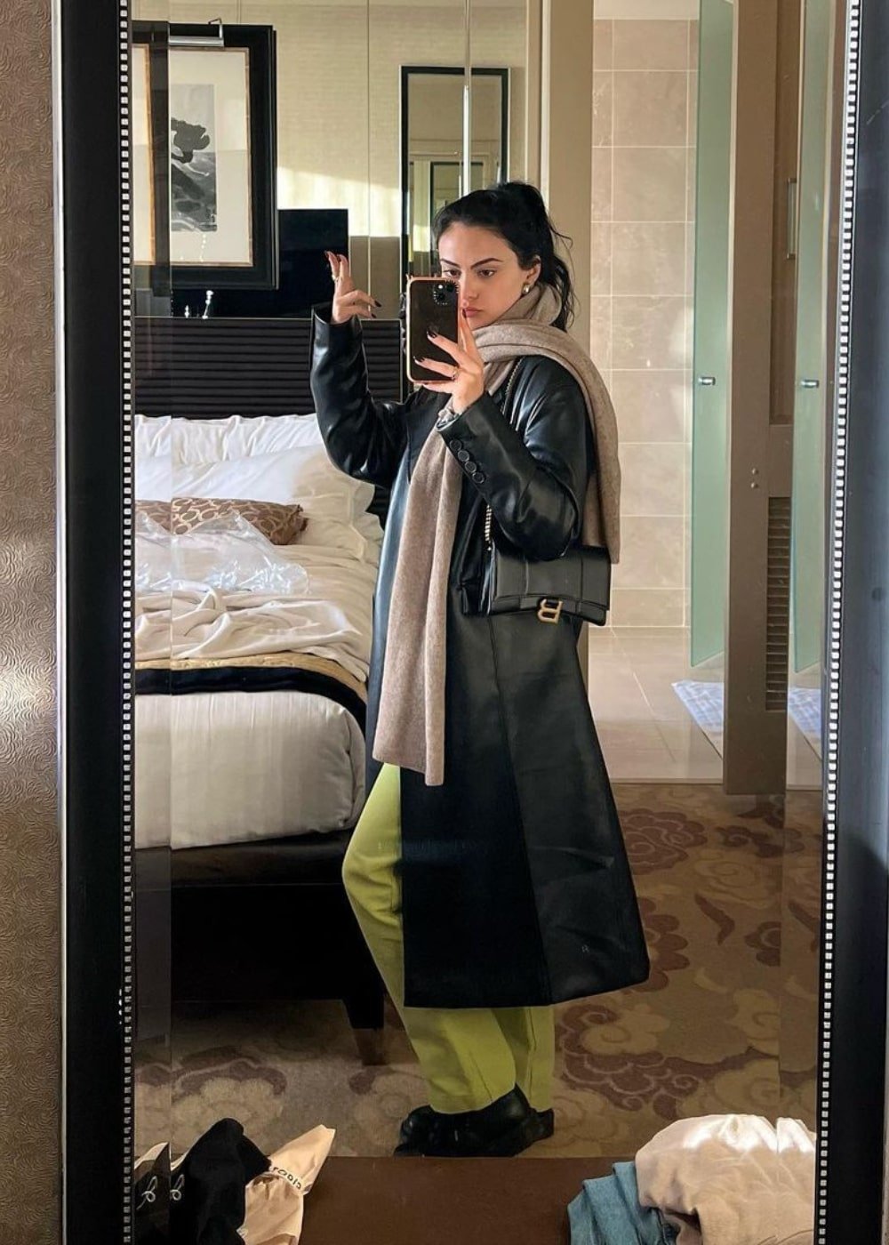 Camila Mendes - calça verde, trench coat preto e cachecol verde - Camila Mendes - Inverno  - foto na frente do espelho - https://stealthelook.com.br
