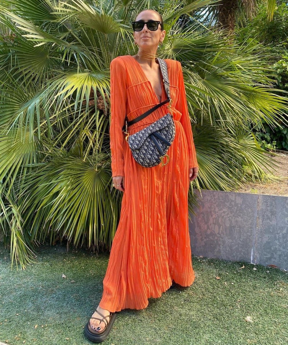 Laura Eguizabal - vestido longo laranja, óculos e bolsa - looks para casamento na praia - Verão - em pé usando óculos de sol - https://stealthelook.com.br