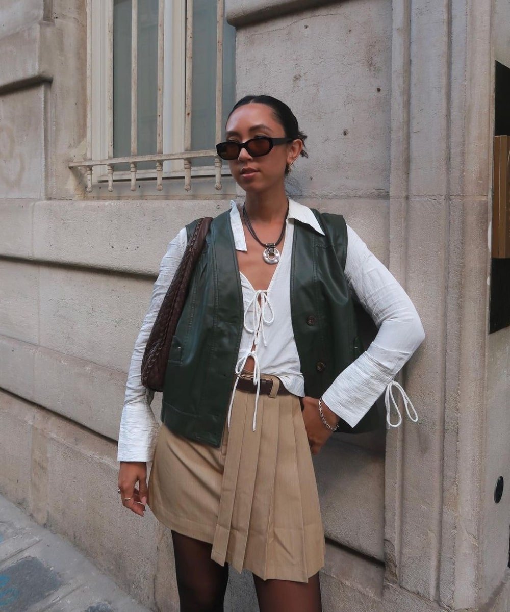 Stephanie Arant - saia, blusa branca e colete de couro verde escuro - peças indispensáveis - Outono - em pé na rua usando óculos de sol - https://stealthelook.com.br