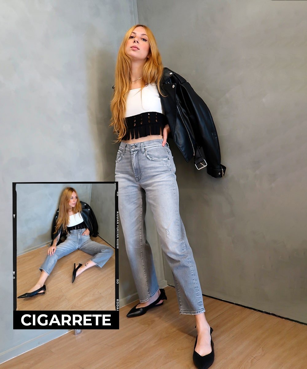 Ali Santos - calça jeans, top branco, jaqueta de couro preta e sapatilhas - calça wide leg - Verão - em pé em uma sala de paredes cinzas - https://stealthelook.com.br