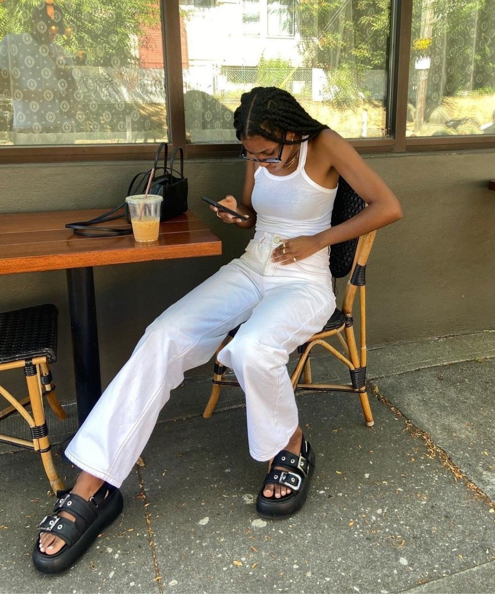 Claire Most - calça branca, regata branca, papete e óculos pretos - looks de verão - Verão - sentada em um café - https://stealthelook.com.br