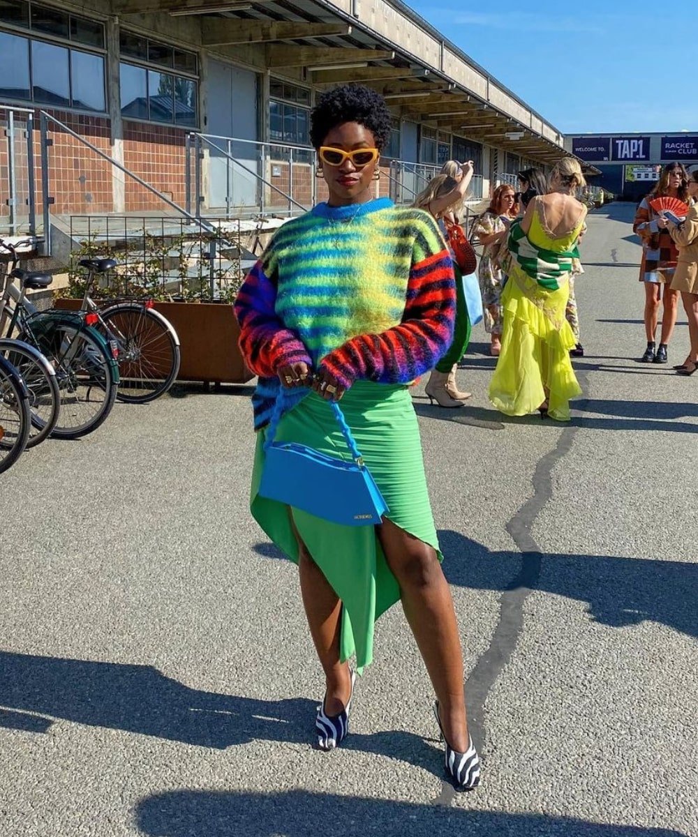 Yolande Macon - saia midi verde drapeada, trico colorido e sapato de zebra print - tendência de moda - Outono - em pé na rua usando óculos de sol - https://stealthelook.com.br