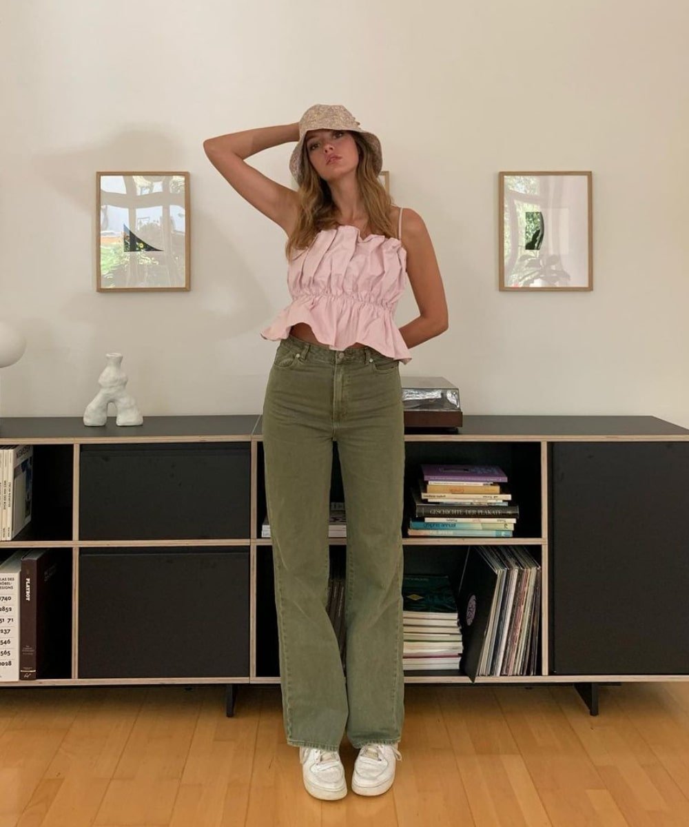 @maryljean - calça verde, blusa rosa drapeada e bucket hat - tendência de moda - Outono - em pé em uma sala - https://stealthelook.com.br