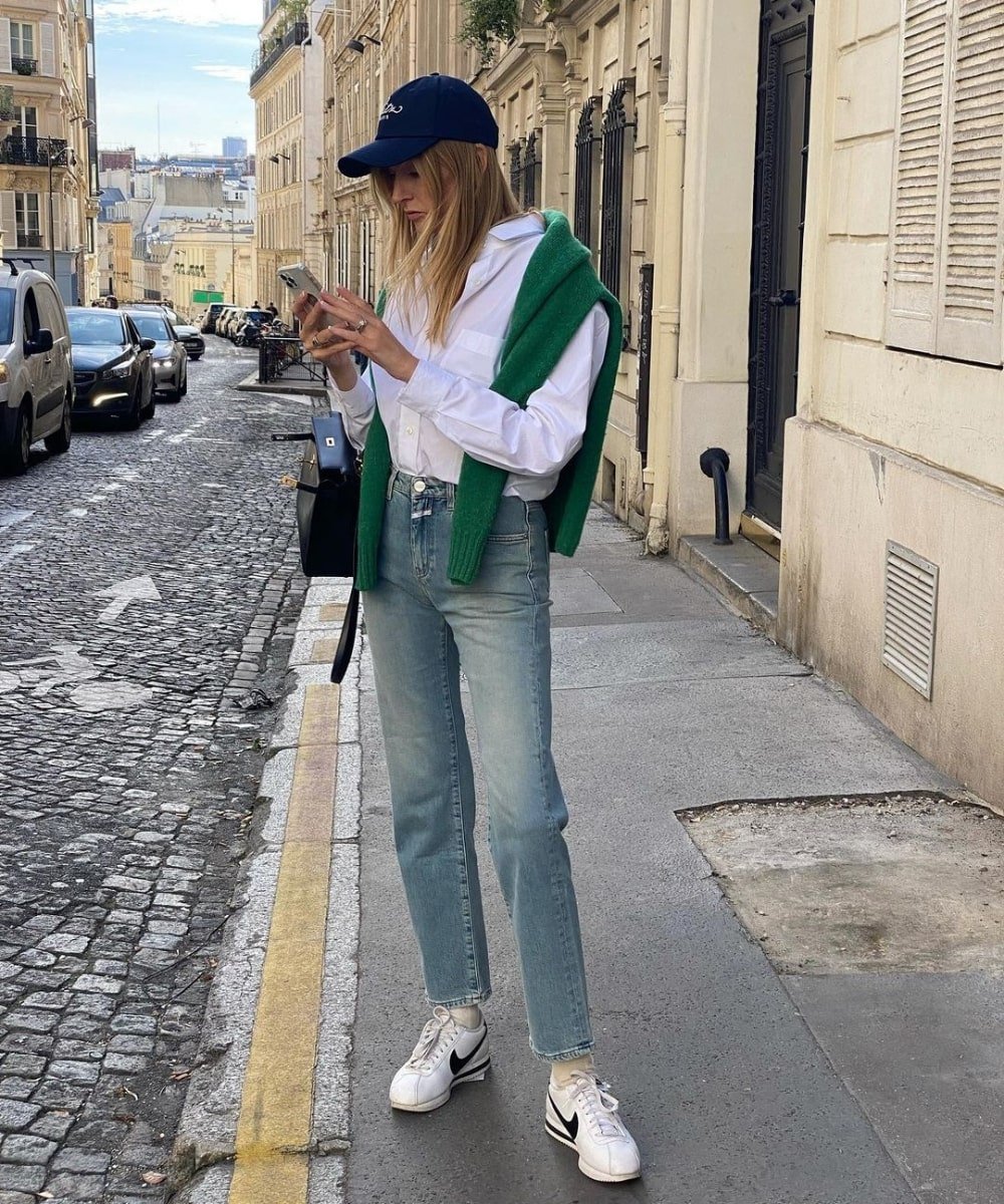 Camille Charriere - calça jeans, camisa branca e boné - tendências de moda - Primavera - em pé na rua - https://stealthelook.com.br