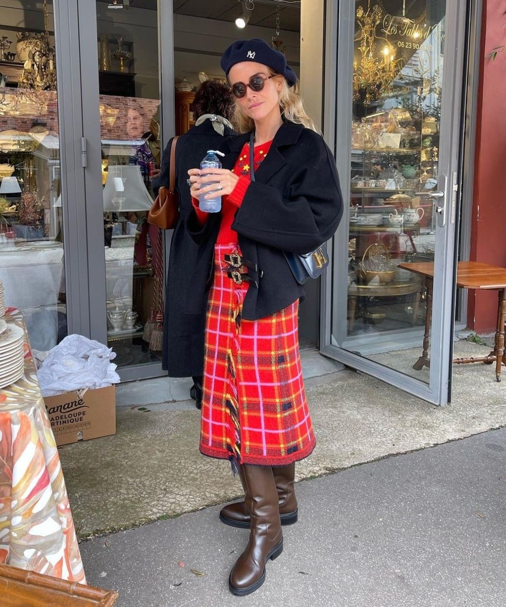 Blanca Miró Scrimieri - saia xadrez, blusa vermelha, jaqueta e botas marrons - Paris Fashion Week - Outono - em pé na rua usando óculos de sol e uma boina - https://stealthelook.com.br