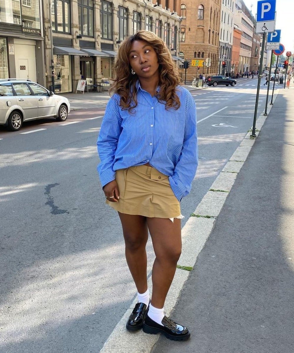Nnenna Echem - camisa azul e minissaia bege - tendências estilosas - Verão - em pé na rua - https://stealthelook.com.br