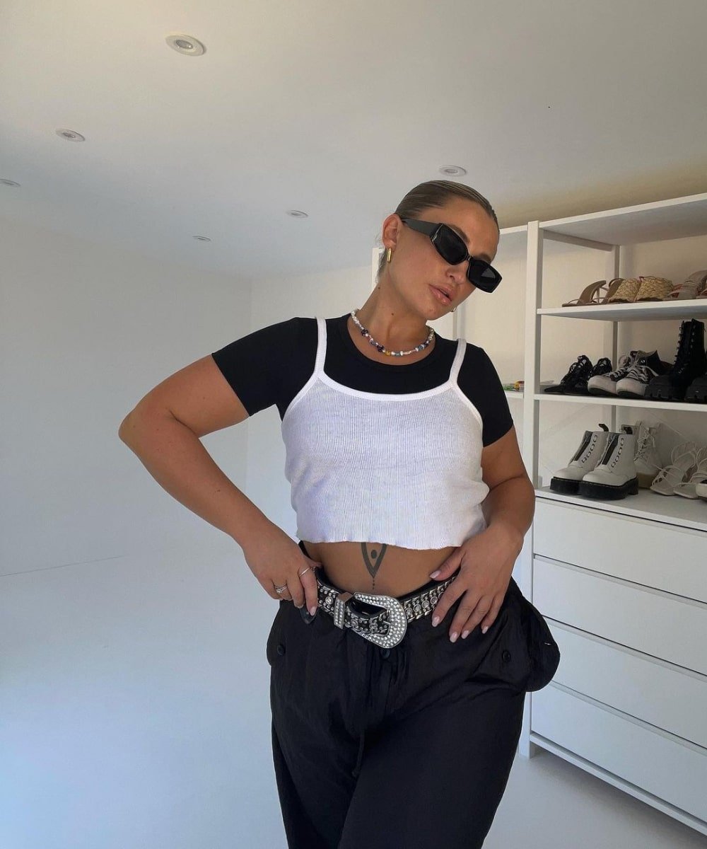 Faye Queenan - calça preta, blusa preta e regata branca - tendências estilosas - Verão - em pé usando óculos de sol - https://stealthelook.com.br