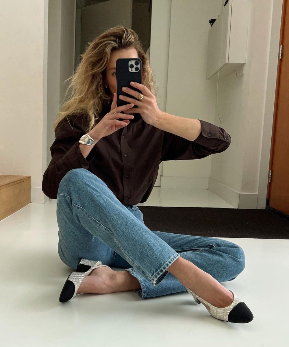 Anouk Yve - calça jeans, blusa preta, sapatilha bicolor e bracelete - anos 80 - outono - sentada e tirando foto na frente do espelho - https://stealthelook.com.br