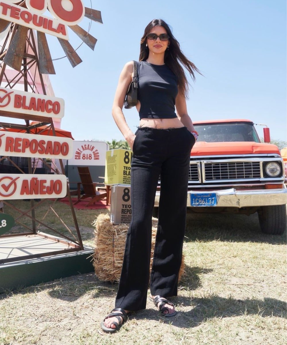 Kendall Jenner - calça preta, regata preta e papetes - looks do Coachella - verão - em pé usando óculos escuros - https://stealthelook.com.br