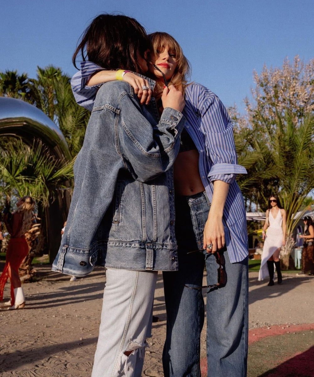 Suki Waterhouse e Camila Morrone - roupas jeans, camisa listrada oversized - looks do Coachella - verão - duas meninas abraçadas em pé - https://stealthelook.com.br
