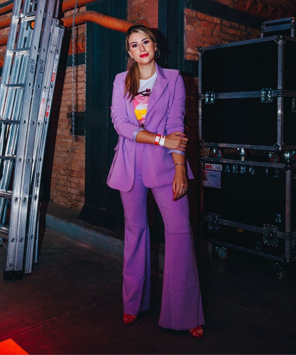 Nina Secrets - conjunto de alfaiataria roxo com blazer e calça comprida - PUSH - verão - em pé na frente de uma parede de tijolos - https://stealthelook.com.br