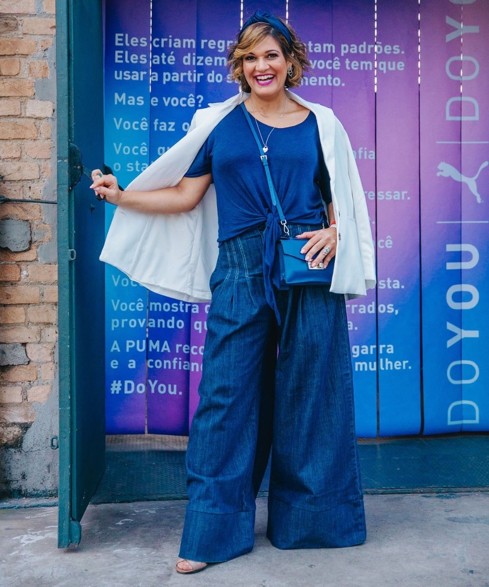 Shana Peixoto - calça pantalona jeans, camiseta azul, blazer branco e bolsa tiracolo azul - PUSH - verão - em pé posando e sorrindo - https://stealthelook.com.br