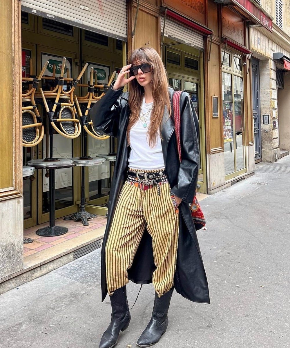 Estelle Pigault Chemouny - calça estampada listrada, botas pretas, casaco preto longo e cintos com strass - tendências do TikTok - inverno - andando na rua - https://stealthelook.com.br