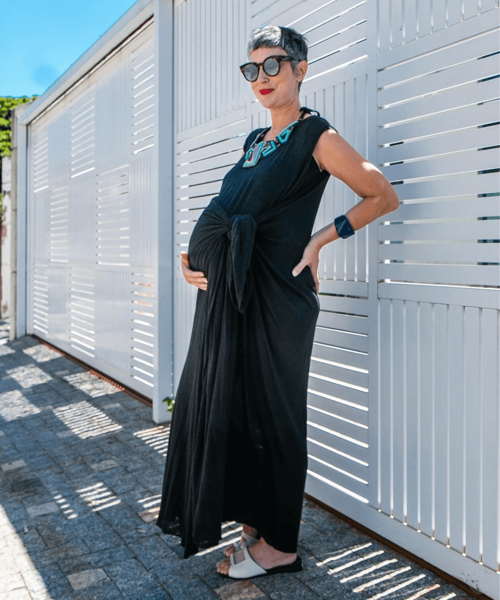 Ana Soares | @modapenochao - vestido longo preto canelado, óculos de sol e papete - pós maternidade - verão - foto de mulher grávida sorrindo com a mão na barriga - https://stealthelook.com.br